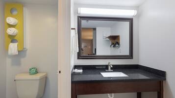 Un baño con un lavabo negro, un espejo y un inodoro.