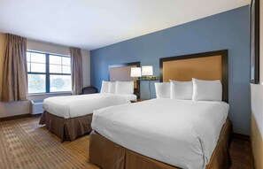 A hotel room with two beds, a large window with curtains, a desk, and a lamp. - Extended Stay America Suites Chicago Romeoville Bollingbrook (Romeoville)