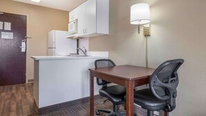 A small kitchenette with a microwave, refrigerator, and sink. There is a wooden table with two chairs and a lamp on the wall. - Extended Stay America Suites Chicago Romeoville Bollingbrook (Romeoville)