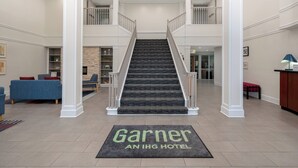 Eine Hotelhalle mit einer zentralen Treppe, einem Empfangsbereich und einer Sitzecke mit blauen Sofas.