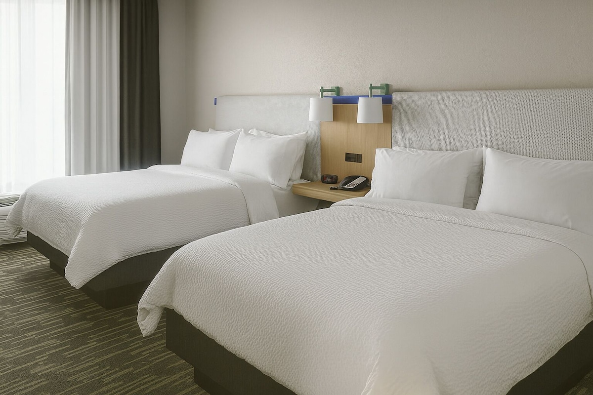 Ein Hotelzimmer mit zwei Betten, einem hölzernen Kopfteil, einem Nachttisch mit Lampe und einem Telefon.
