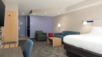 Une chambre d’hôtel comprenant un lit, un canapé, une chaise, une petite table et un téléviseur.