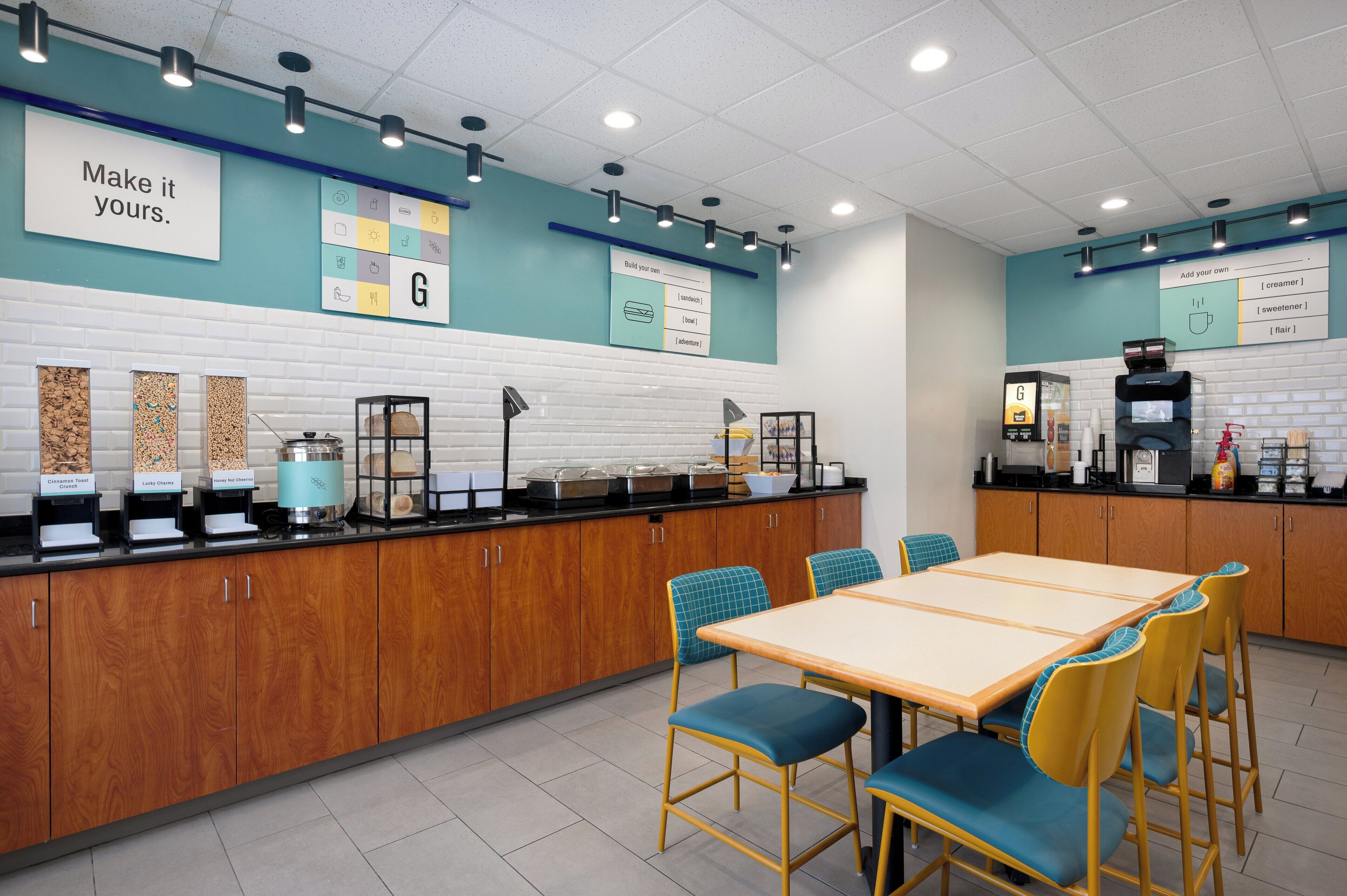 Una cafetería con una barra alargada, diversas opciones de asientos y una pizarra con el menú.