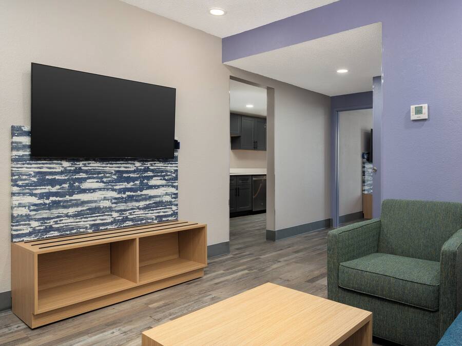 A modern living room with a flat-screen TV, a wooden entertainment unit, and a green armchair.
