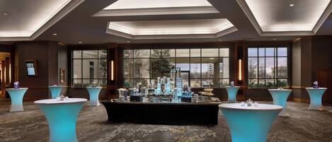 A spacious room with a central bar area, large windows, and a high ceiling with skylights.