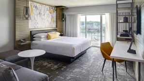 Una habitación de hotel moderna con una cama grande, una pequeña mesa redonda, un sofá y un escritorio.