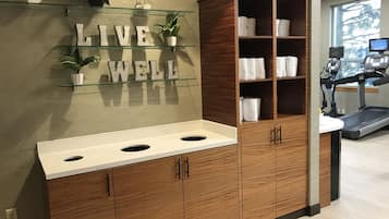 A bathroom with a wooden vanity, a glass shelf with plants, and a motivational sign saying "LIVE WELL".