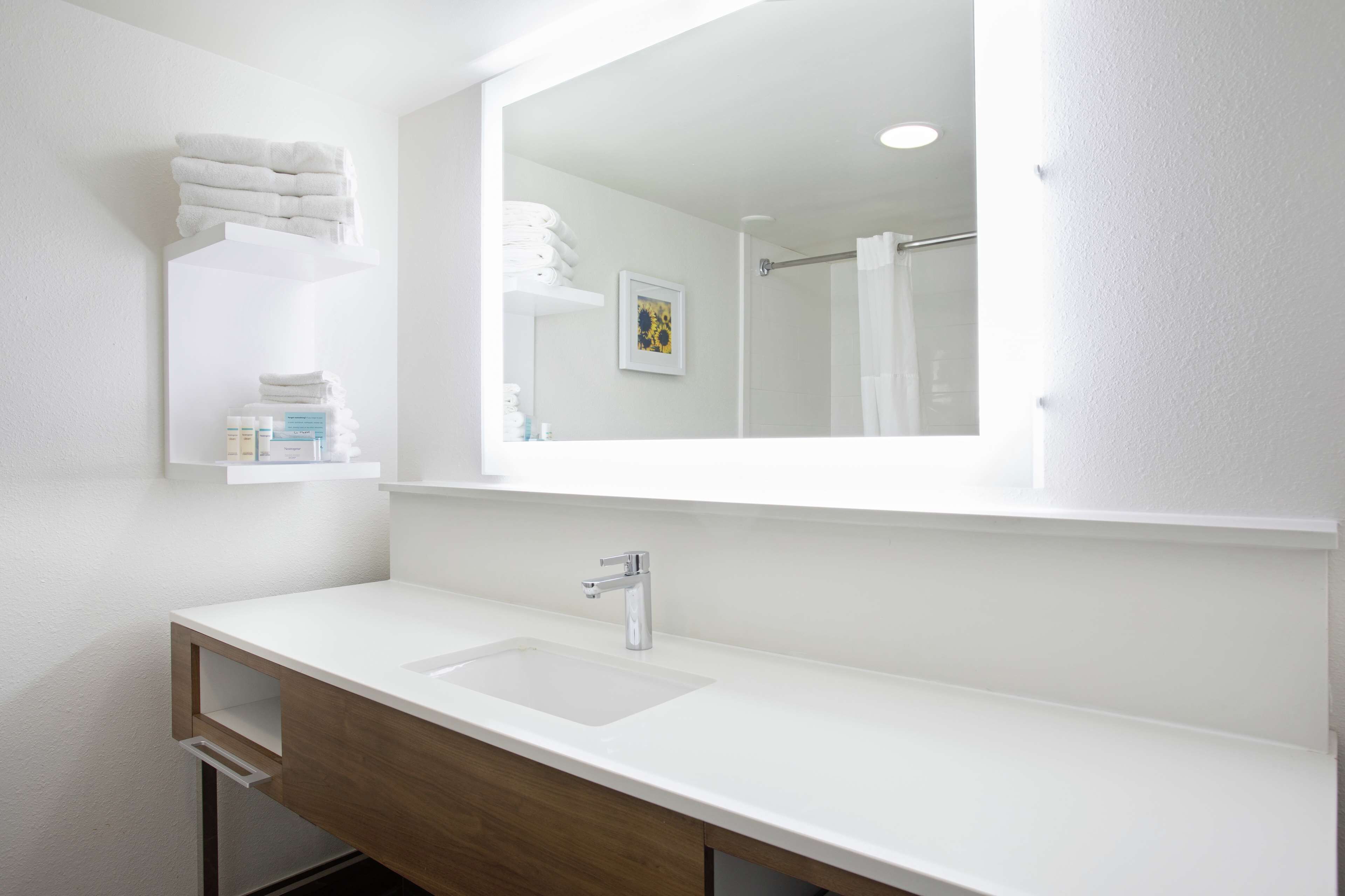 A modern bathroom with a white sink, wooden vanity, and a large mirror.