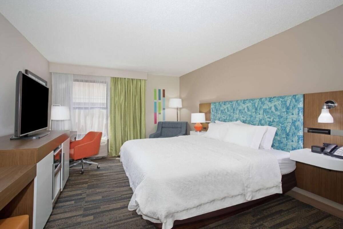 A hotel room with a bed, desk, television, and two chairs.