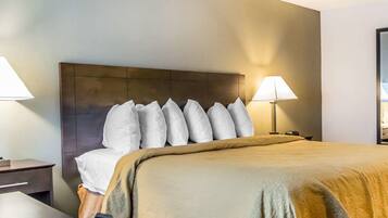 A hotel room with a large bed, a nightstand, a desk, and two lamps.