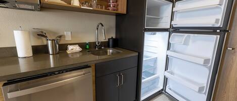 A compact kitchen with a dishwasher, a sink, and a double-door refrigerator.
