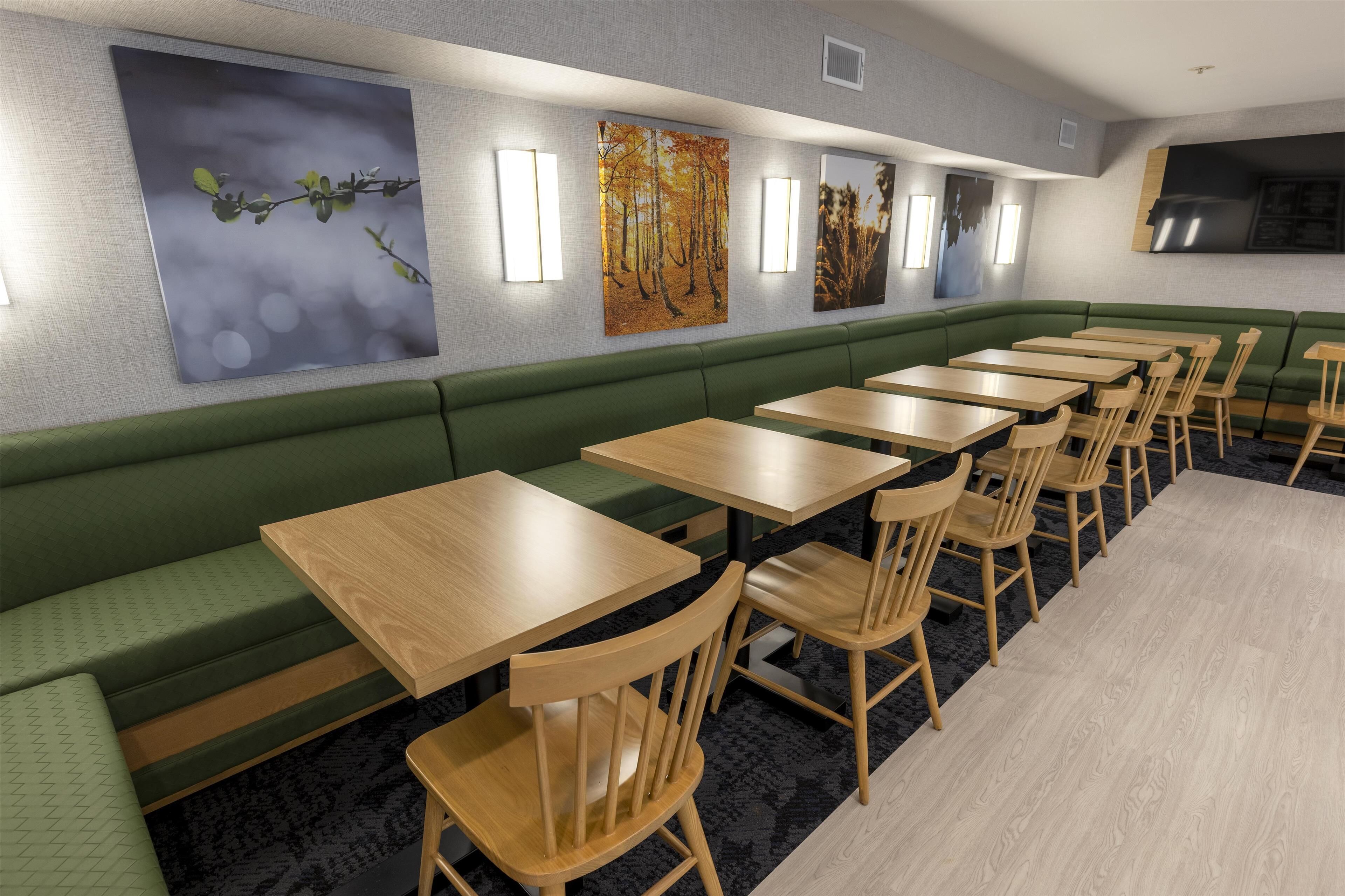 A restaurant with green booths, wooden tables, and chairs.