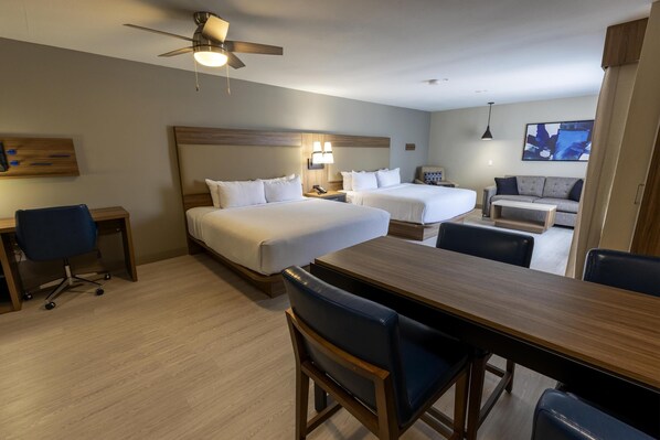 Habitación de hotel con dos camas, un escritorio, una mesa de comedor y un sofá.