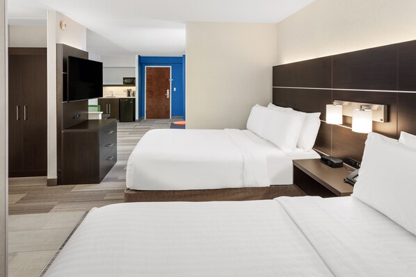 A hotel room with a bed, bedside table, TV, and a kitchenette in the background. - Holiday Inn Express Hotel & Suites South Portland by IHG (South Portland)