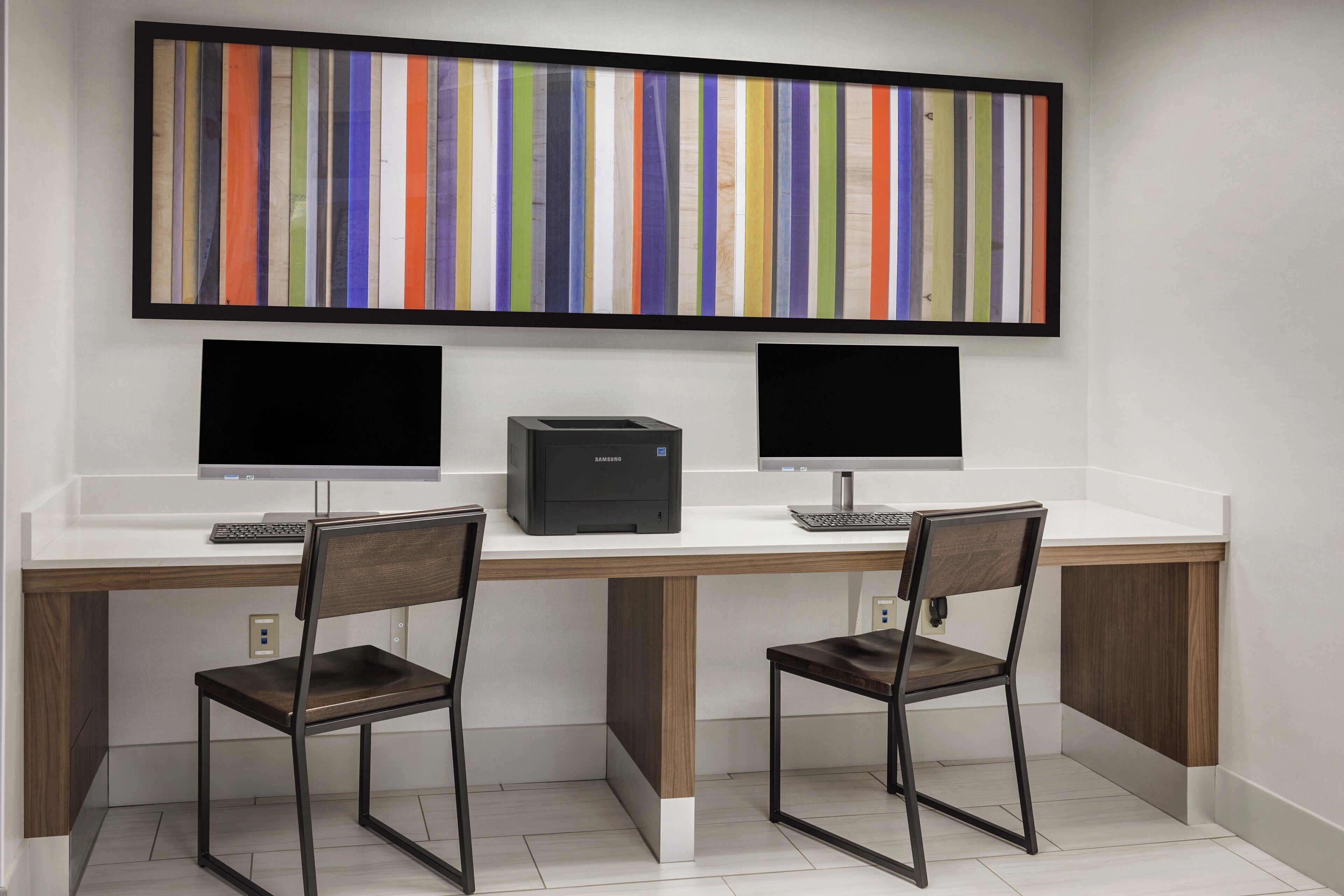 Un espacio de trabajo con dos escritorios, cada uno con monitor de computadora, teclado y silla.