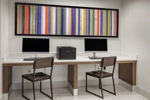 Un espacio de trabajo con dos escritorios, cada uno con monitor de computadora, teclado y silla.