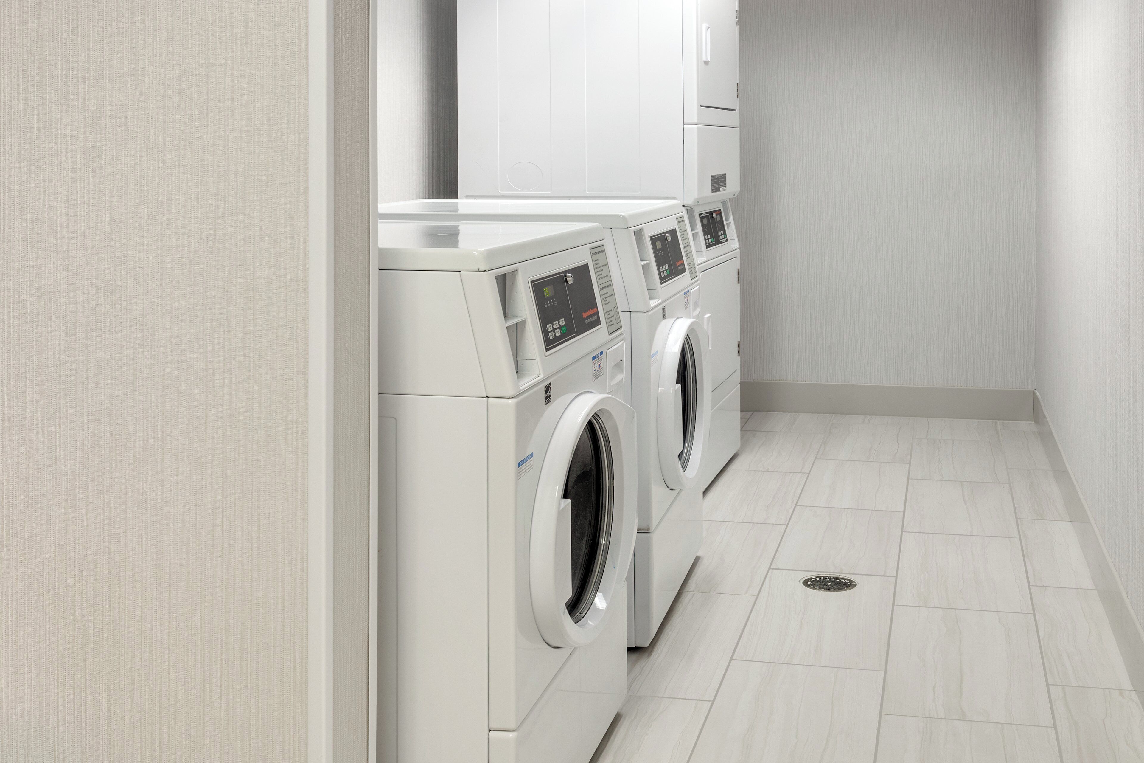 A laundry room with three stacked washing machines and a dryer.