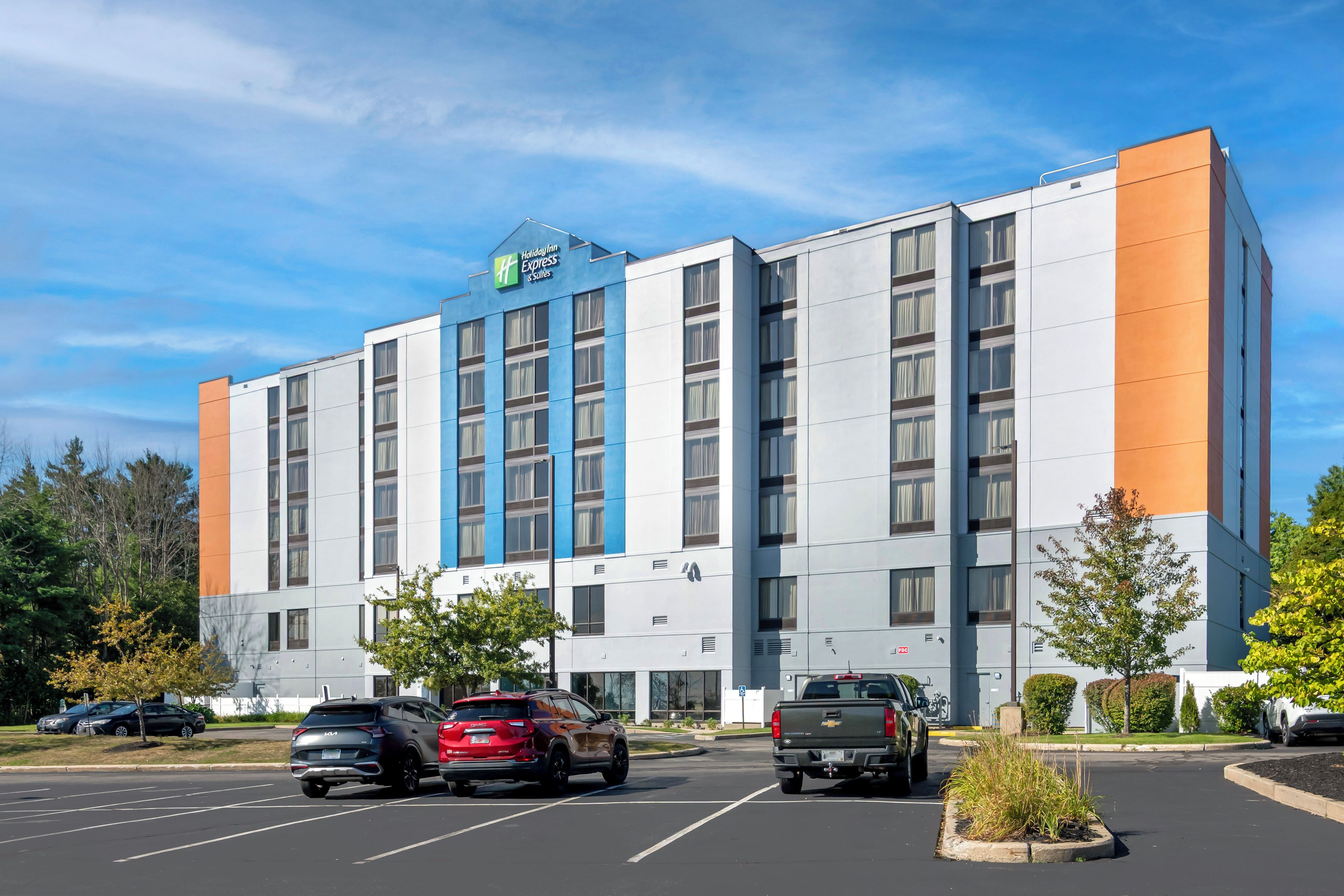 A Holiday Inn Express & Suites hotel with a parking lot and several vehicles.