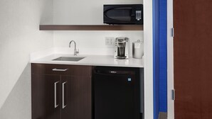 Une cuisine compacte équipée d’un four à micro-ondes, d’une machine à café et d’un lave-vaisselle.