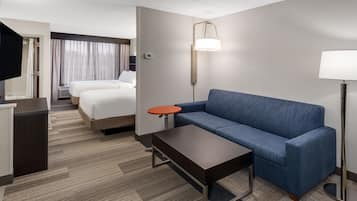 A hotel room with a bed, a blue sofa, a small table, a TV, and a lamp.