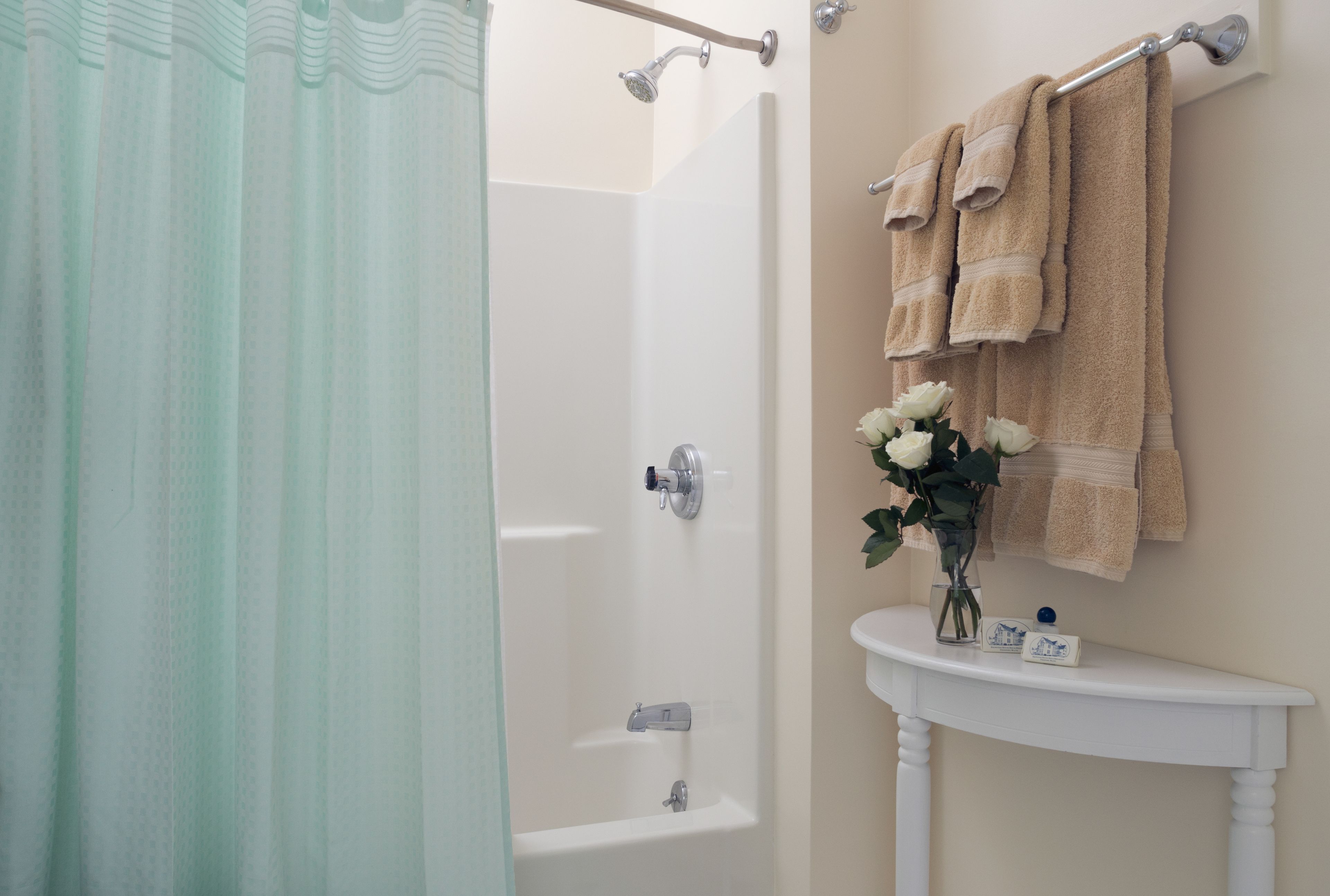 A bathroom with a shower, a sink, and a towel rack with towels.