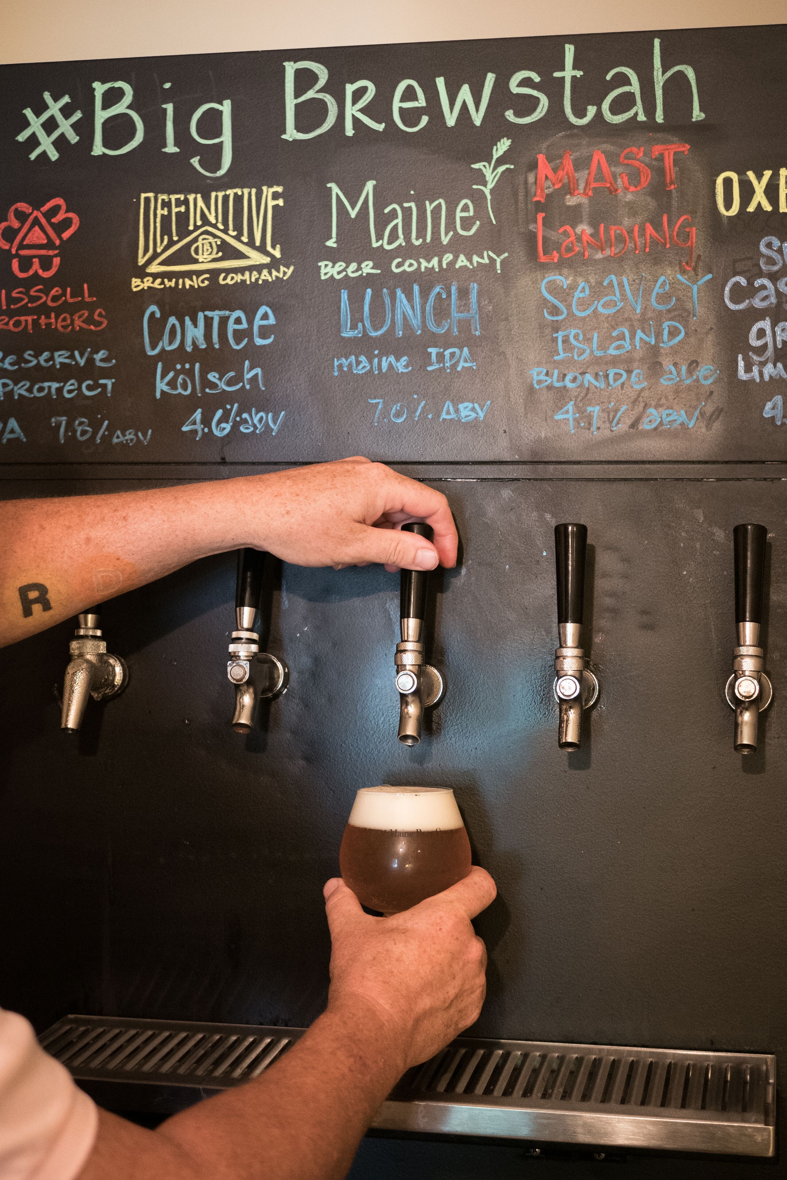 A beer tap area with various taps and a hand selecting a beer.