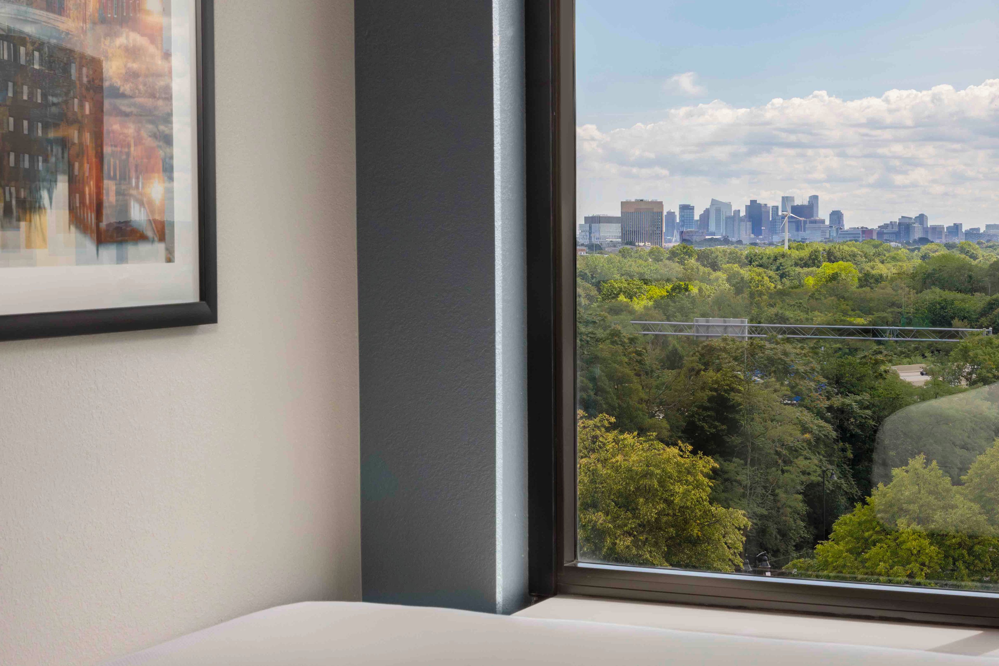 Una habitación con un ventanal grande que ofrece vistas a un horizonte urbano y a un parque.