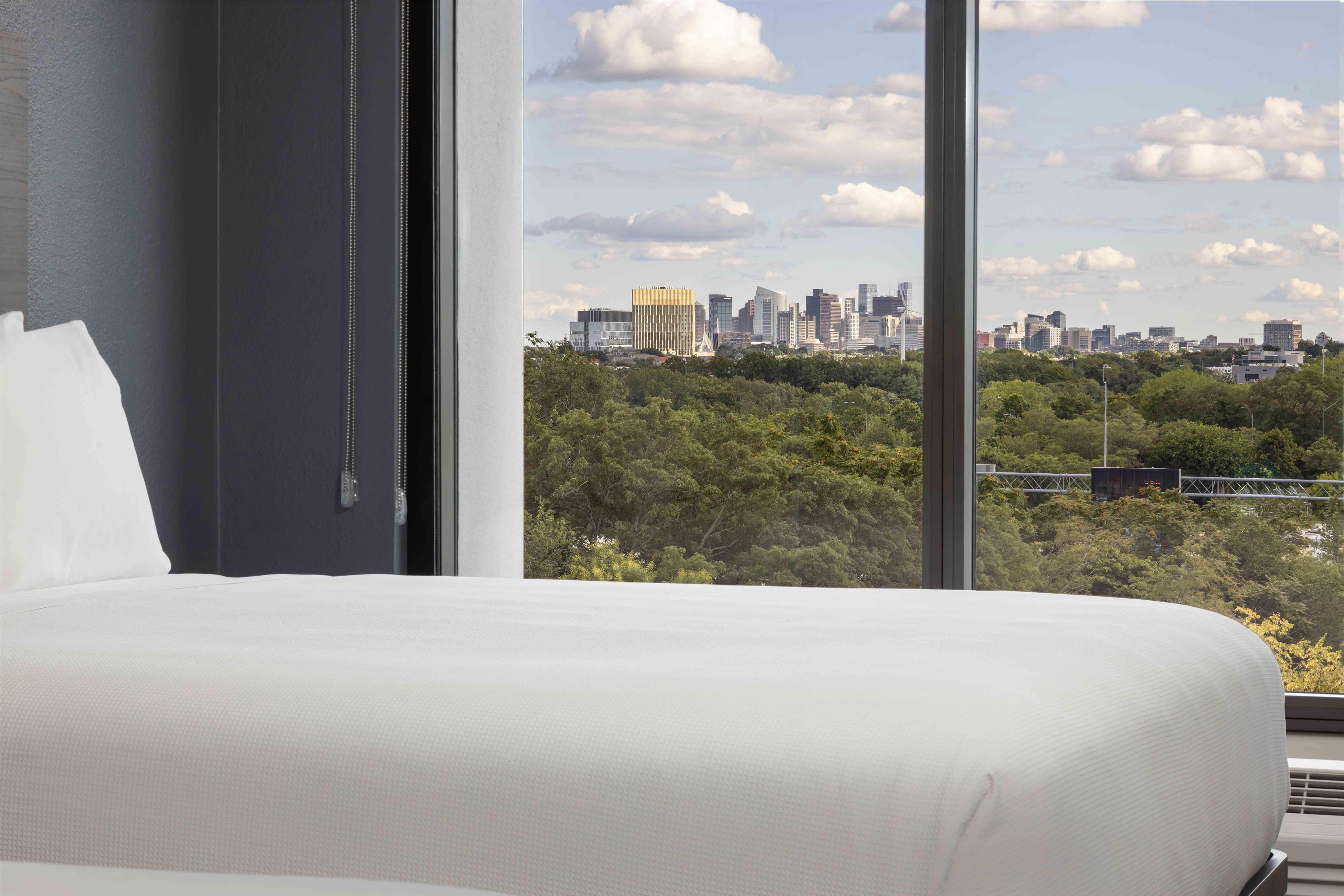 Habitación de hotel con un amplio ventanal y vista al horizonte de la ciudad.