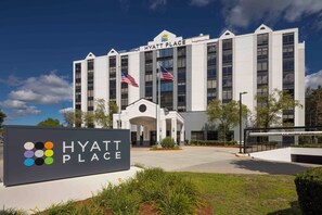 A Hyatt Place hotel with a prominent entrance, American flags, and a signboard. - Hyatt Place Boston/Medford (Medford)
