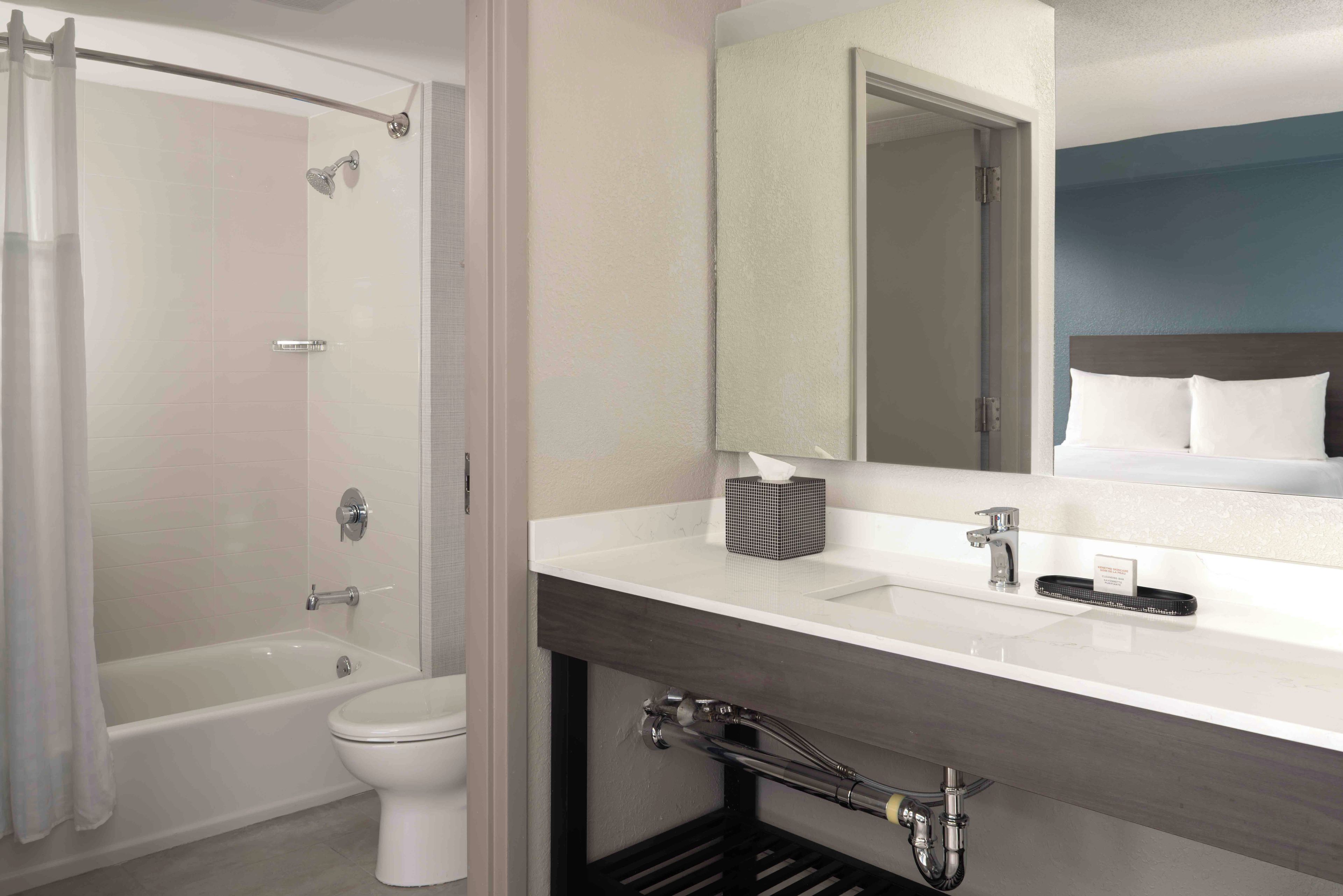 A modern bathroom with a bathtub, toilet, and a vanity with a mirror.