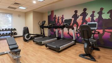 A gym with treadmills, dumbbells, and a wall mural of runners.