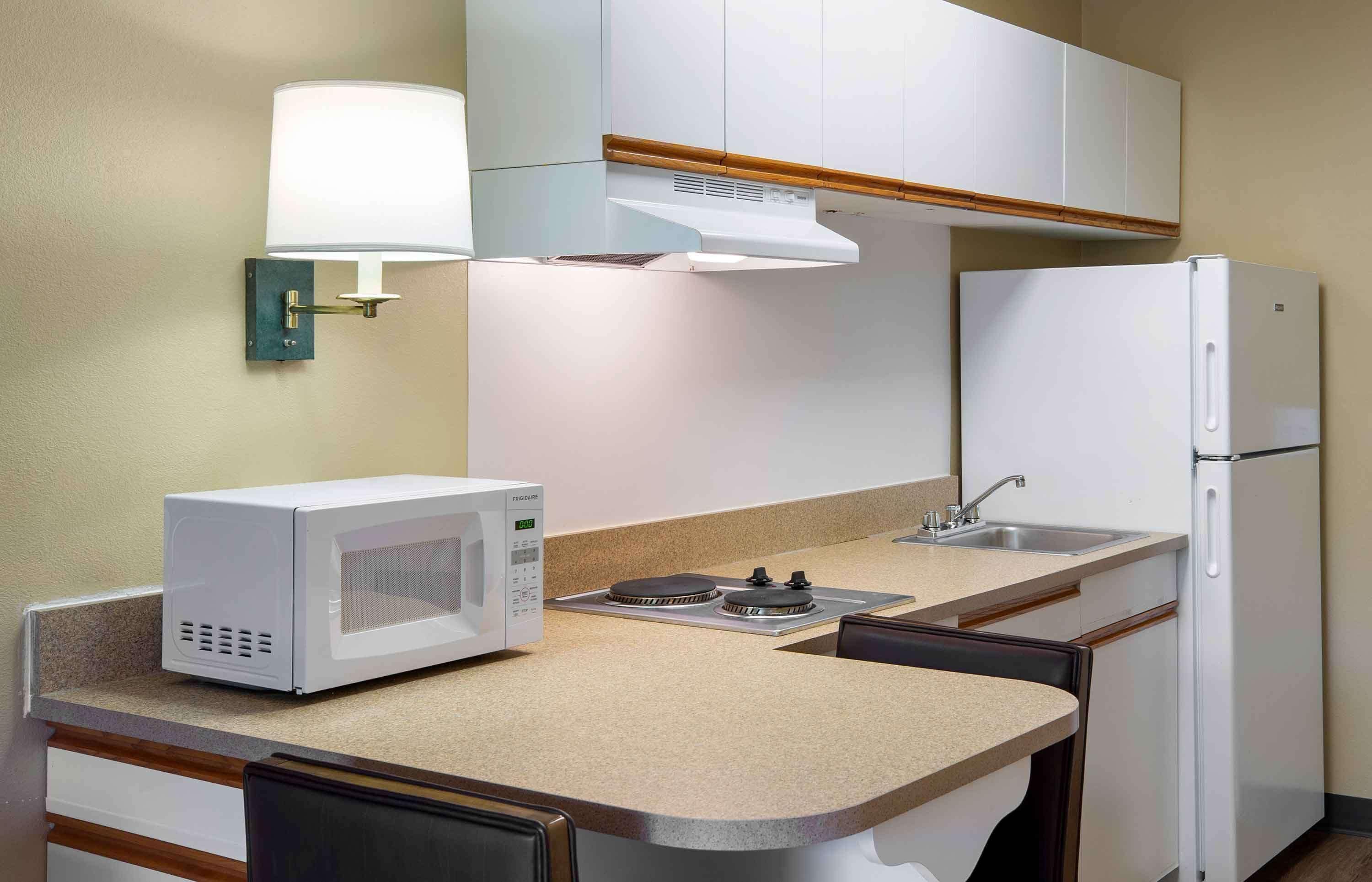 A compact kitchenette with a microwave, stove, sink, and refrigerator.
