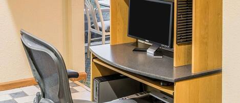 Un espacio de trabajo con computadora, impresora y silla.