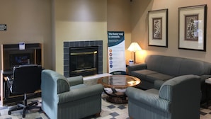 A hotel lobby with a fireplace, seating area, and a sign about rewards program. - Quality Inn Kalamazoo near Wings Stadium (Kalamazoo)