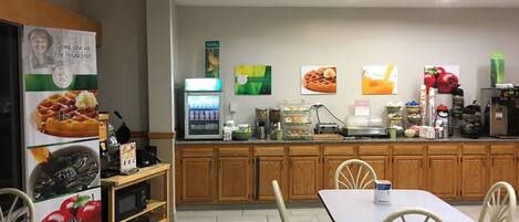 Un comedor con mostrador, refrigerador y zona de estar con sillas y mesa.