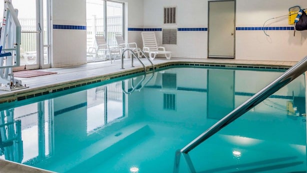 An indoor swimming pool with clear water, a ladder, and lounge chairs. - Quality Inn Kalamazoo near Wings Stadium (Kalamazoo)