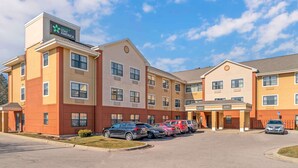 A hotel with multiple buildings, a parking lot with cars, and a clear sky.