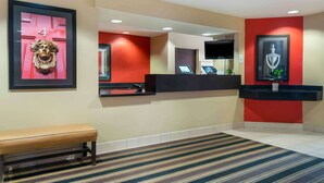 A reception area with a bench, a reception desk, a large mirror, and framed artwork on the walls.