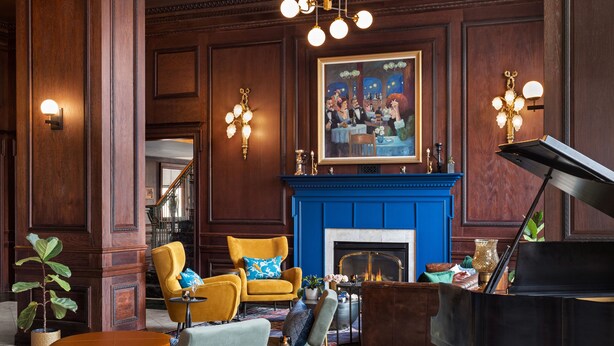 A grand lobby with a blue fireplace, a grand piano, and classic decor. - Landmark Inn (Marquette)