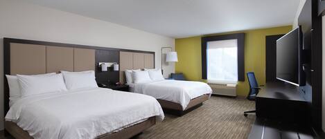 A hotel room with two beds, a desk with a flat-screen TV, a chair, and a window with blinds.