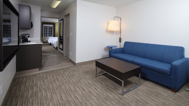 Ein Hotelzimmer mit Küchenzeile, einem blauen Sofa, einem Couchtisch und einer Lampe.
