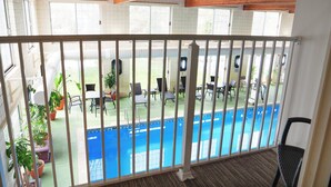 A balcony with a view of a swimming pool, wooden beams, and potted plants. - Holiday Inn Express Grand Rapids SW by IHG (Grandville)