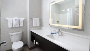 Ein modernes Badezimmer mit Toilette in Weiß, einem großen Spiegel und einem schwarzen Waschtisch.