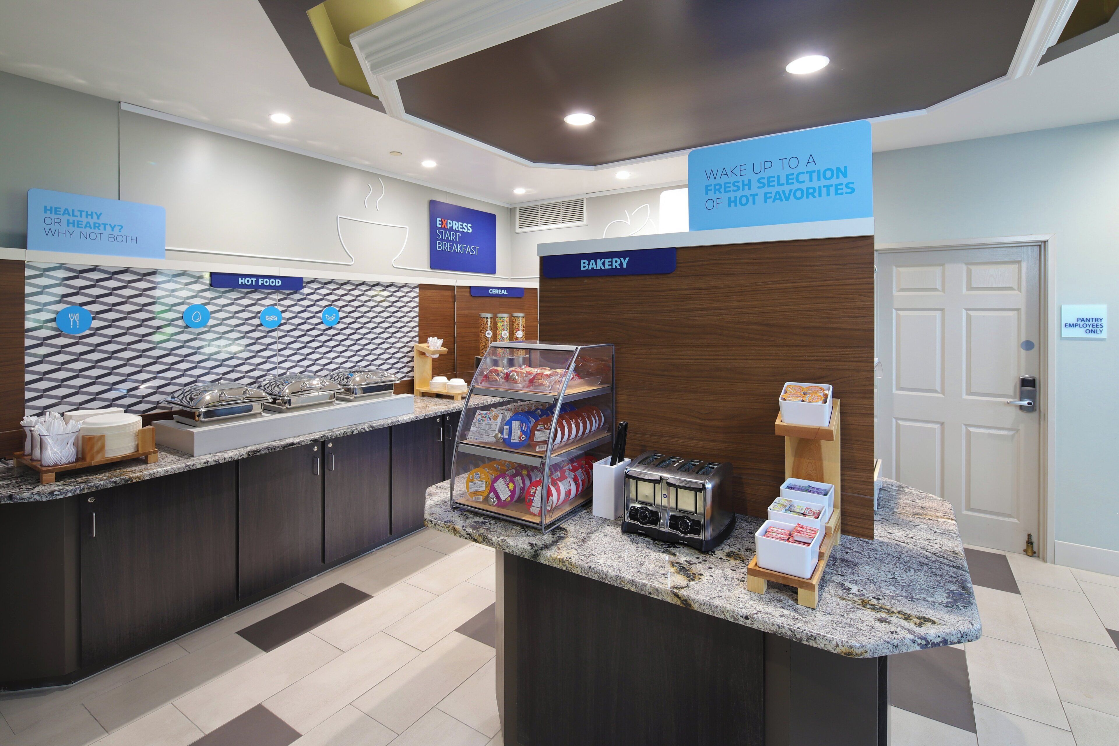 A breakfast area with a self-serve hot food station, a bakery section, and a sign indicating a selection of fresh favorites.