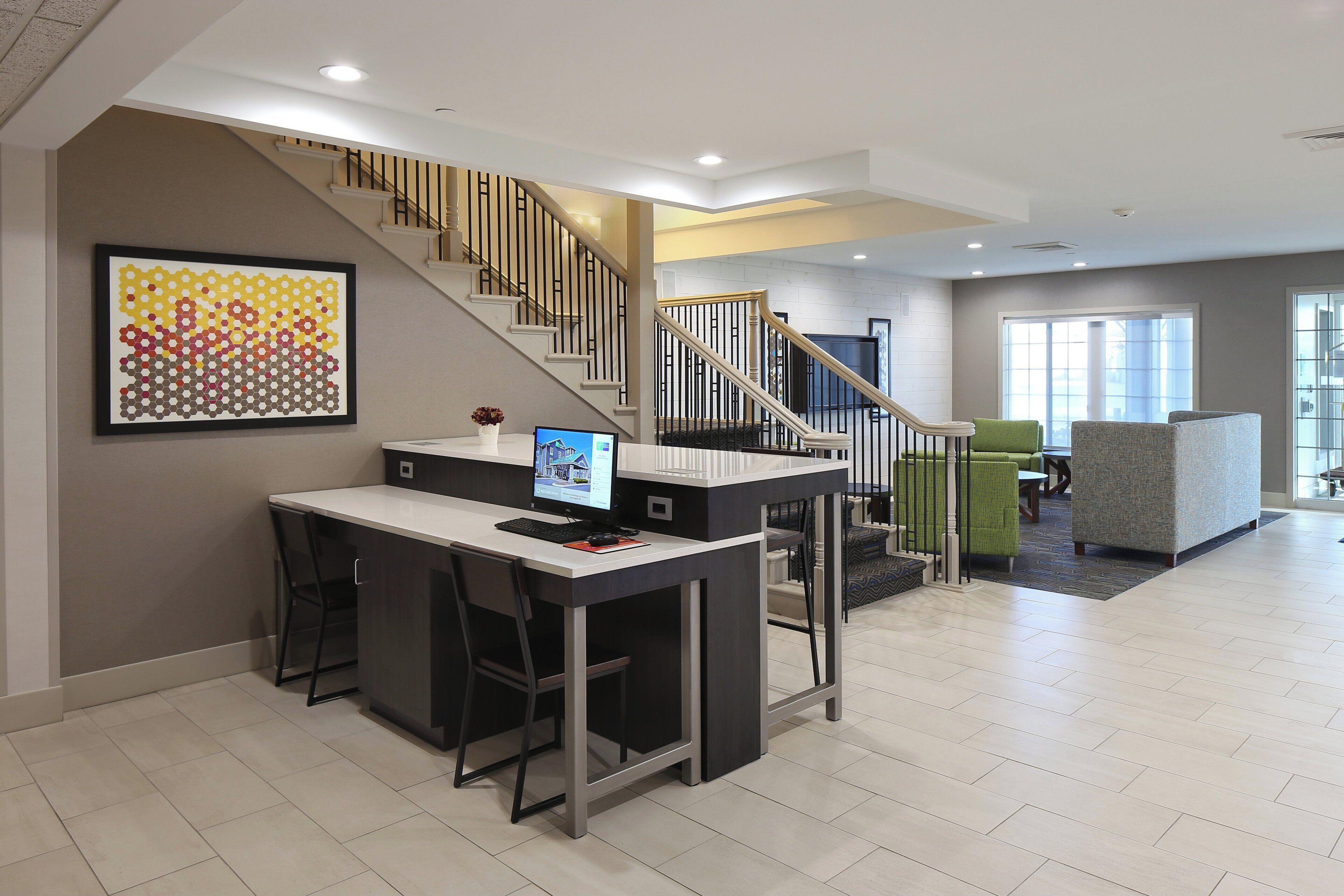 Ein modernes Interieur mit Treppe, Schreibtisch inklusive Computer und einem großen abstrakten Gemälde.