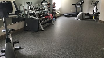 Un gimnasio con cintas de correr, elípticas y equipo de levantamiento de pesas.