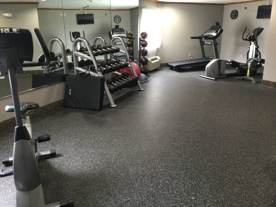 Un gimnasio con cintas de correr, elípticas y equipo de levantamiento de pesas.