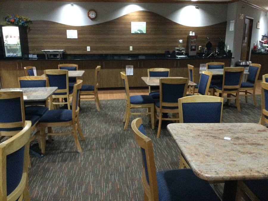 Un restaurante con mesas y sillas de madera, una barra y un reloj en la pared.