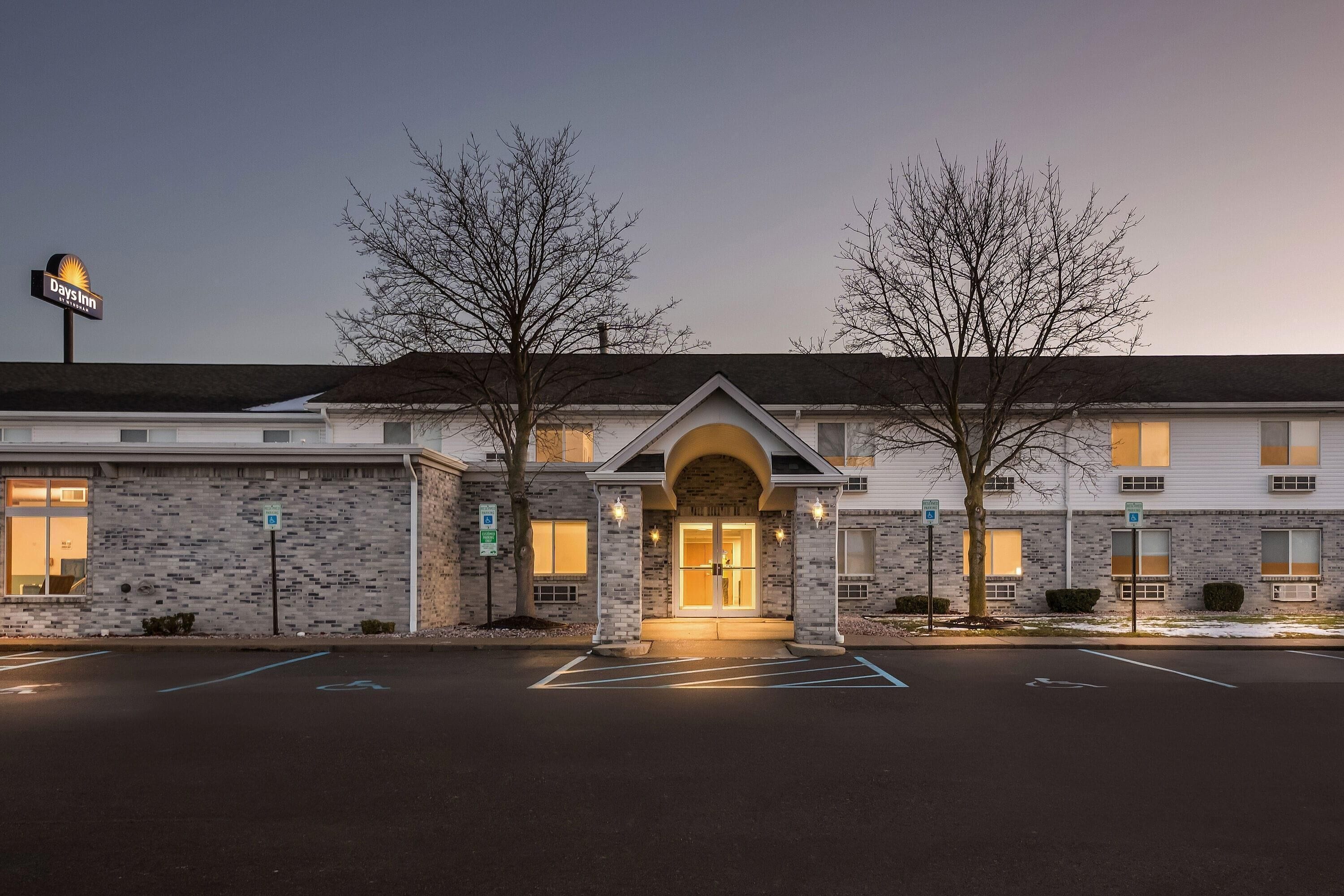 Un hôtel Days Inn avec une façade en briques, une entrée centrale en forme d’arc et un parking.