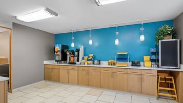 A modern kitchen with wooden cabinets, a blue accent wall, and various appliances.